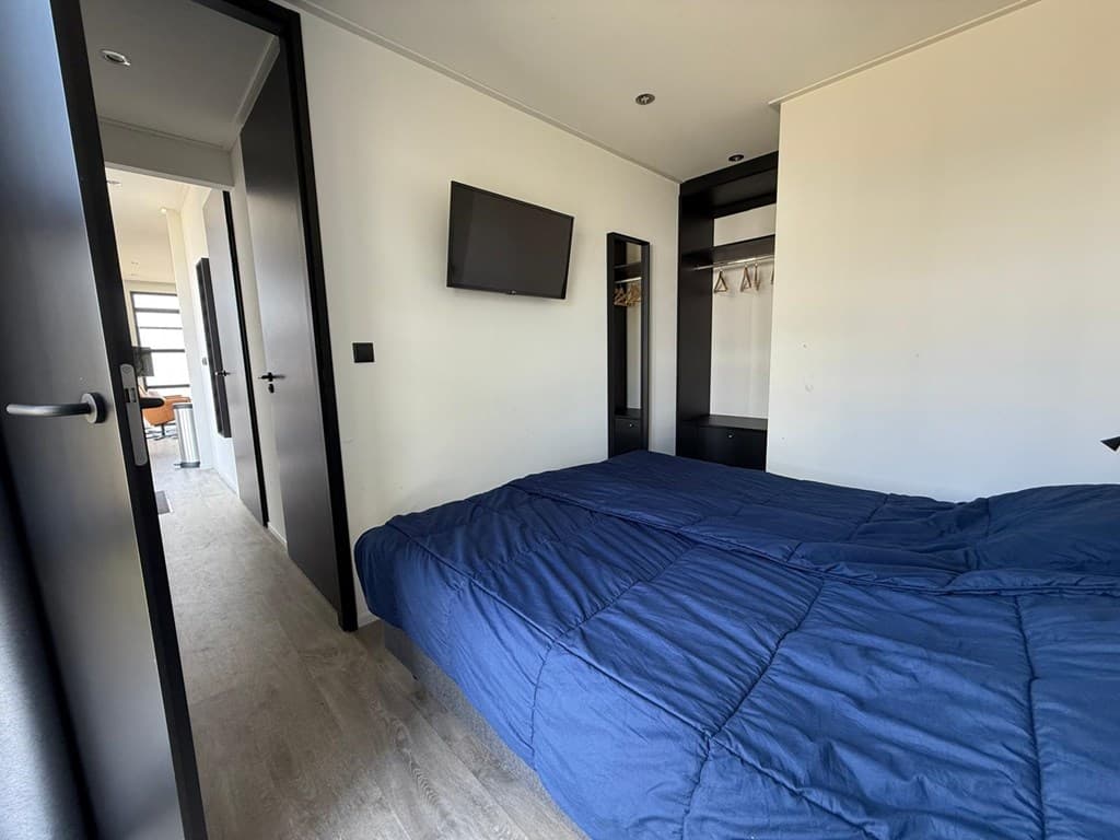 Slaapkamer met een groot bed, kledingkast en een televisie aan de muur