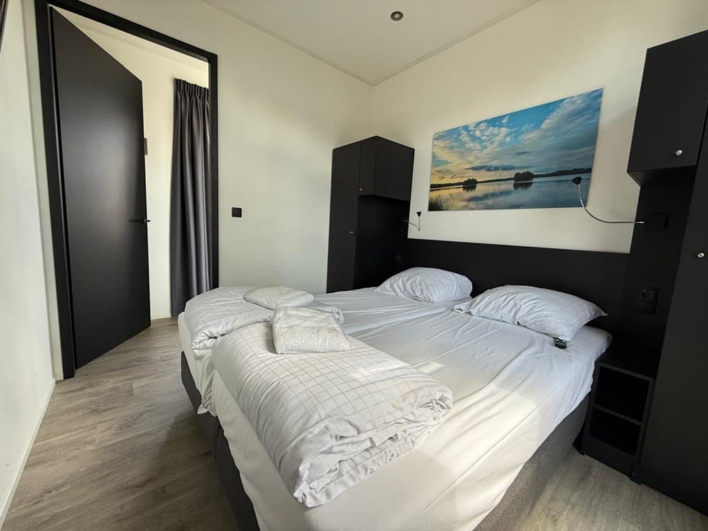 Slaapkamer met twee eenpersoonsbedden, nachtkastjes en een schilderij van een landschap aan de wand