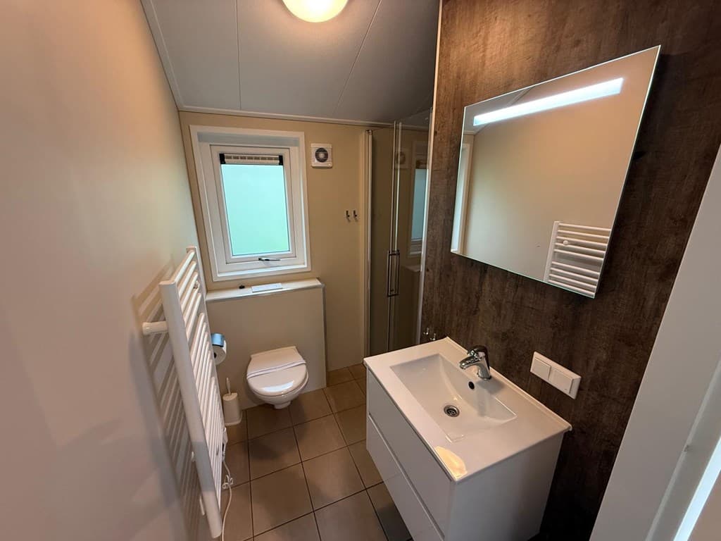 Moderne badkamer met douche, wastafel en toilet, voorzien van een raam en een handdoekenradiator