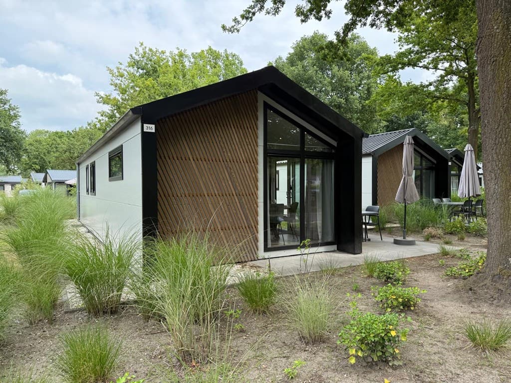 Moderne vakantiewoning met grote ramen, houten gevelbekleding en omringd door groen in EuroParcs Kaatsheuvel.