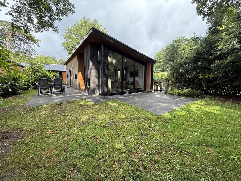 Moderne woning met grote glazen wand, terras en tuin met gras en bomen in Park Berkenrhode, Wekerom