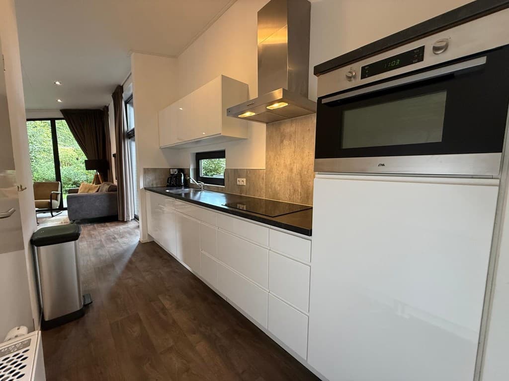 Moderne open keuken met witkeukenkasten, een oven en een uitzicht op de woonkamer met grote ramen.