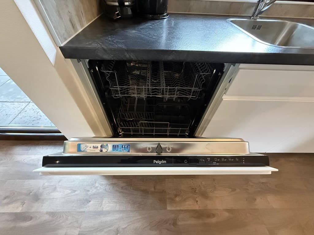 Ingebouwde vaatwasser met open deur en zichtbare inhoud in moderne keuken.