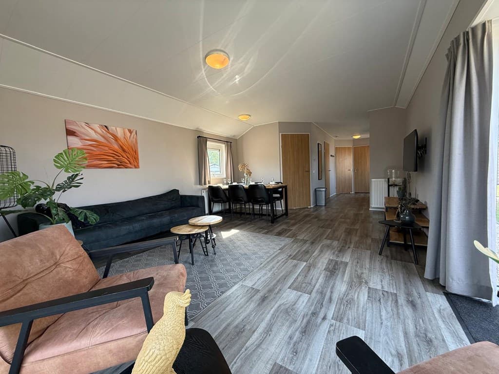 Inpandige woonkamer met zithoek, eetgedeelte en modern interieur met houten vloeren en grote ramen