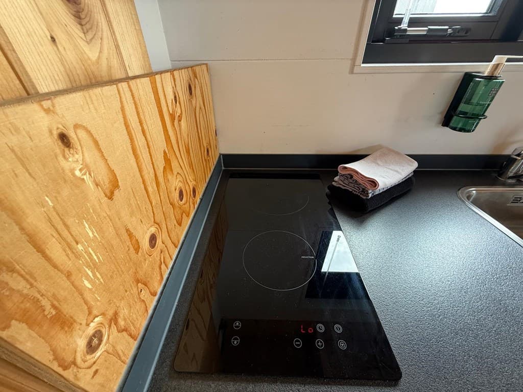 Moderne keuken met een inductiekookplaat, houten wandafwerking en een aanrecht met handdoeken in verschillende kleuren.