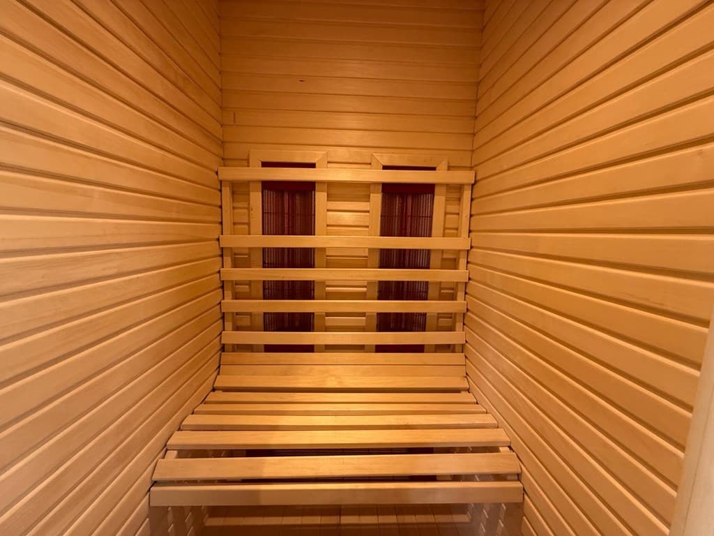 Sauna met houten banken en wandbekleding, in warme tinten van natuurlijk hout.