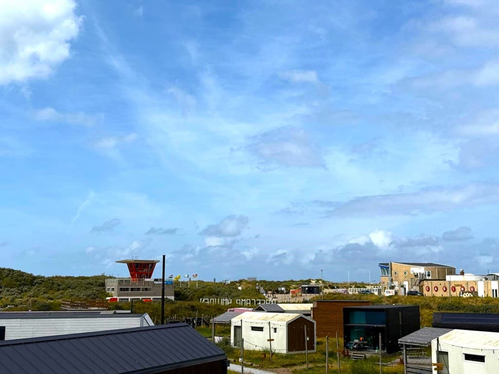 Uitzicht op de omgeving van BaseCamp Ijmuiden met moderne woningen en een helderblauwe lucht