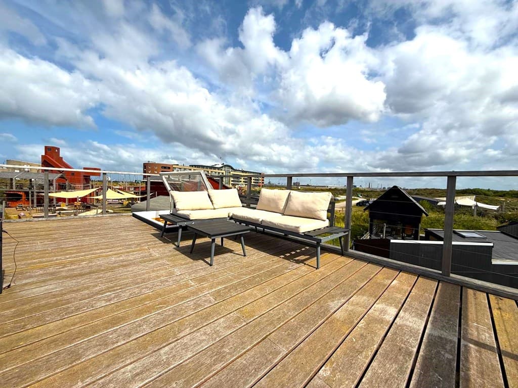 Zonnige dakterras met ligbedden en uitzicht op de omgeving met wolkenluchten