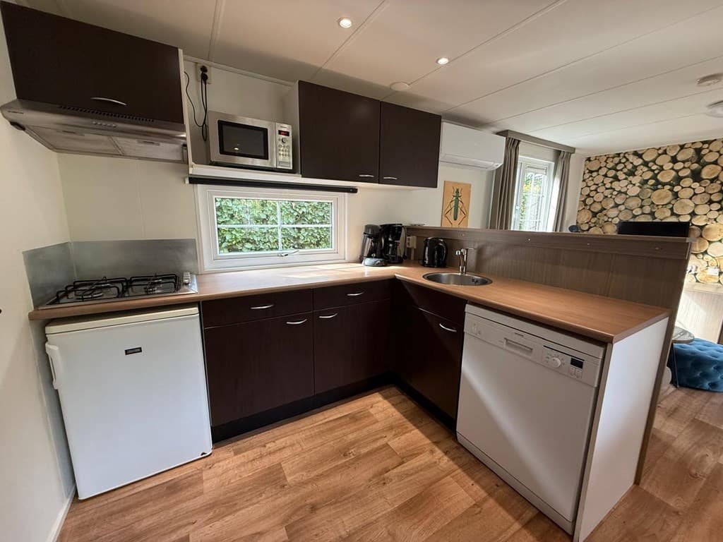 Moderne keuken met houten werkblad, inbouwapparatuur en een raam met uitzicht op groen.