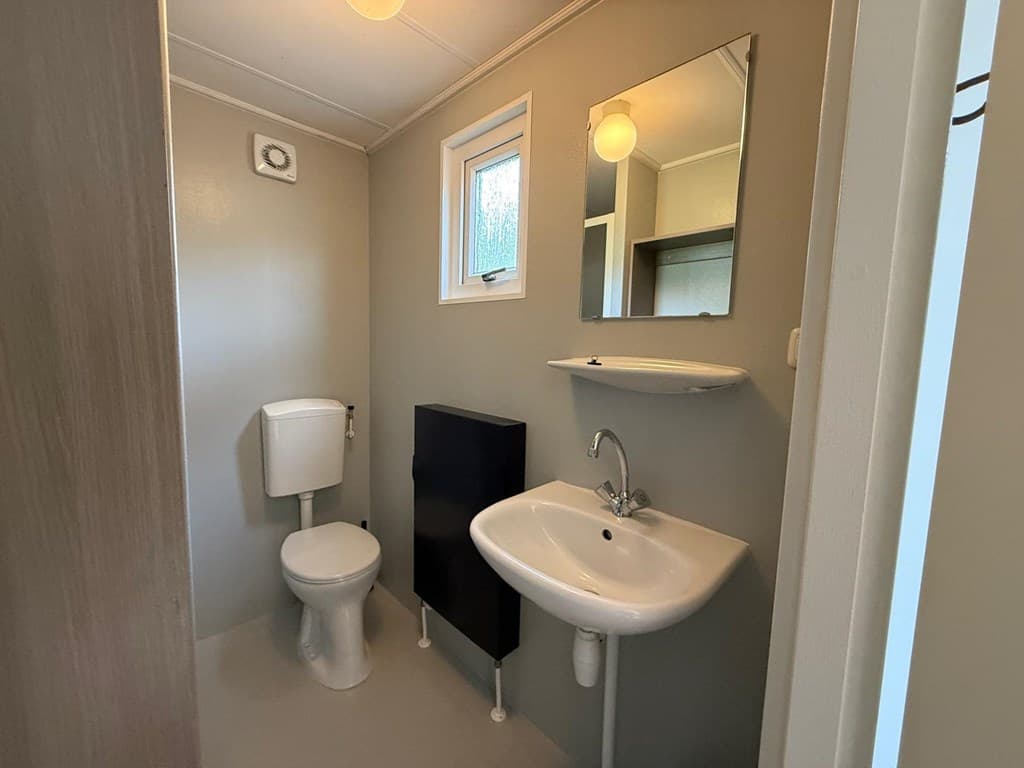 Moderne badkamer met toilet, wastafel en spiegel op een lichte, neutrale muur