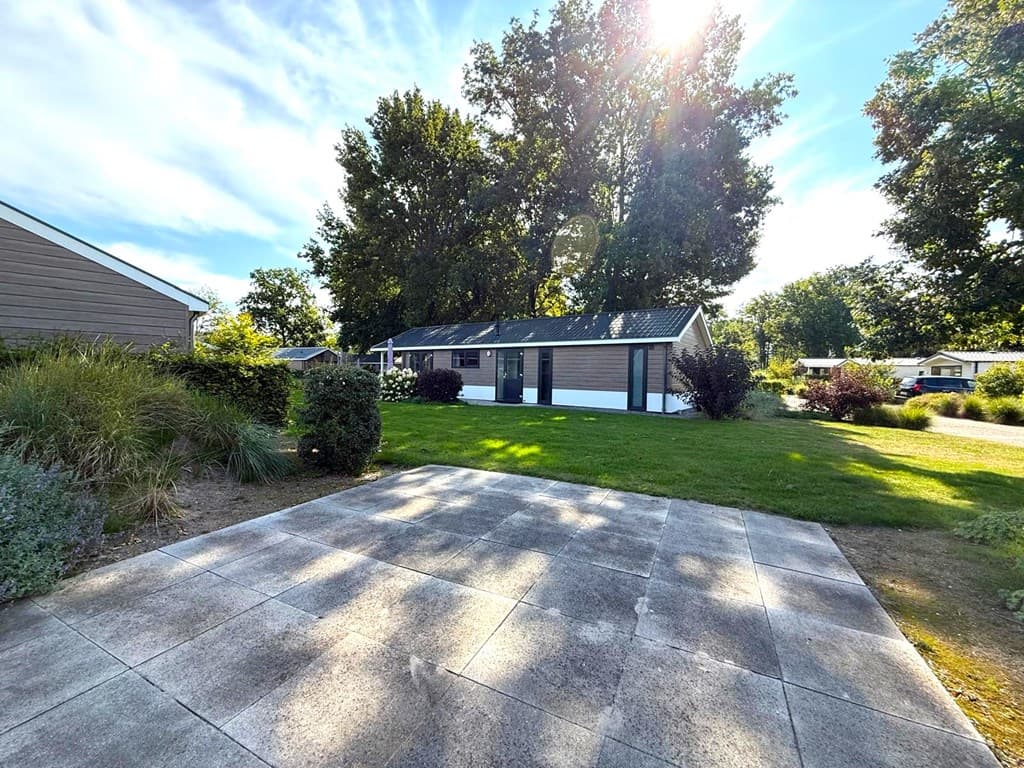 Vakantiehuis met een tuin en terras, omringd door groen en bomen in EuroParcs Zuiderzee.