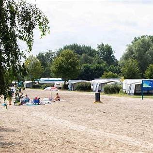 Zicht op een rustige camping met huurtenten, bomen en een zandpad tussen de percelen in EuroParcs Zuiderzee.
