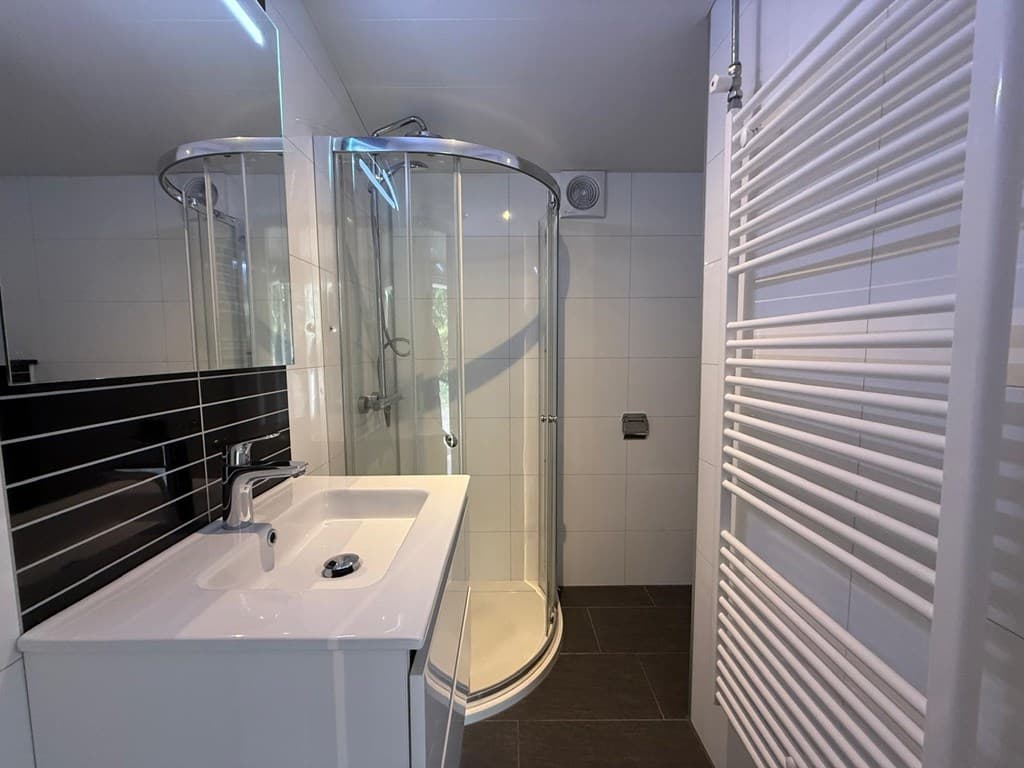 Moderne badkamer met inloopdouche, wastafel en handdoekradiator in neutrale kleuren
