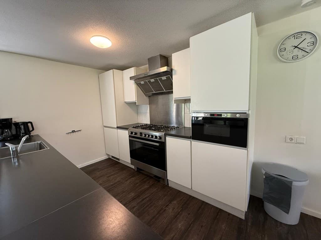 Moderne keuken met inbouwapparatuur, gasfornuis, oven en wastafel, ruimte met houten vloer en halogeenverlichting