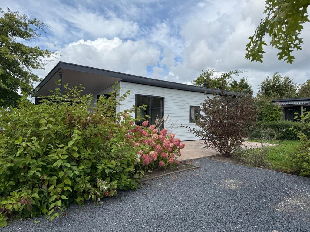 Moderne vakantiewoning omgeven door groen en bloemen met een betegeld terras en witte muren