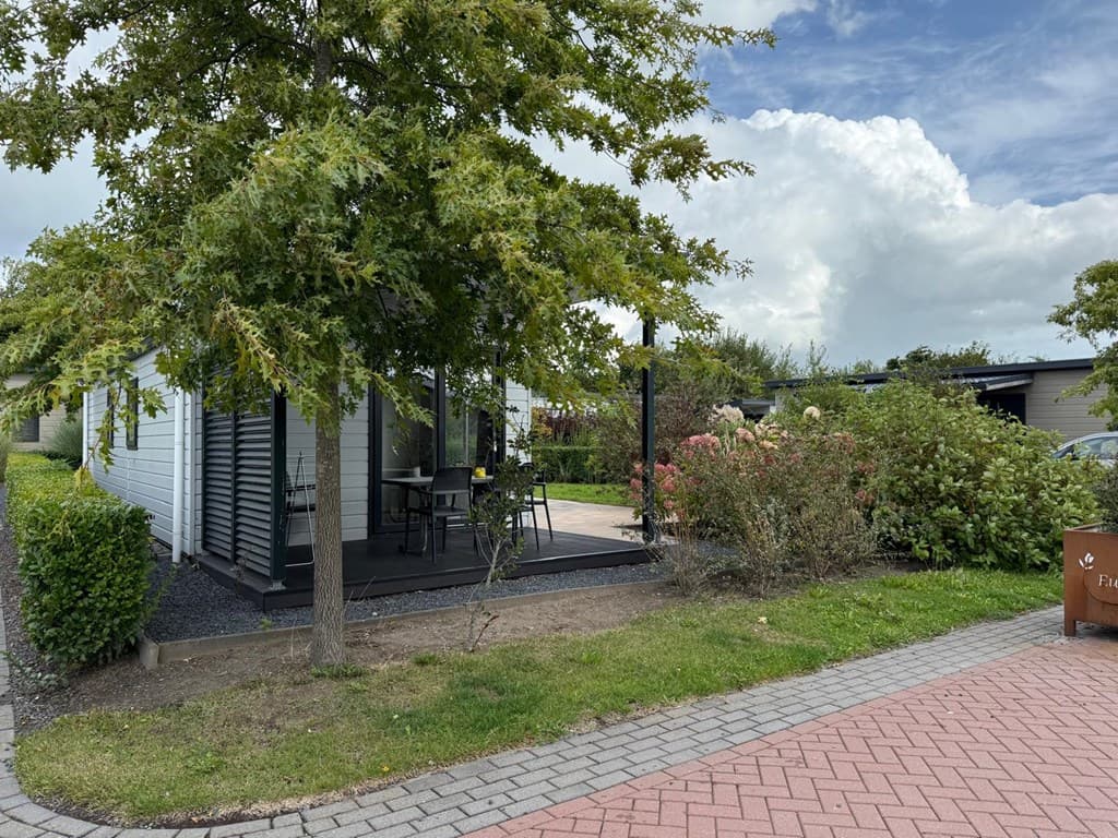 Houten vakantiewoning met terras, omringd door groen en een grindpad in EuroParcs Markermeer, Bovenkarspel.