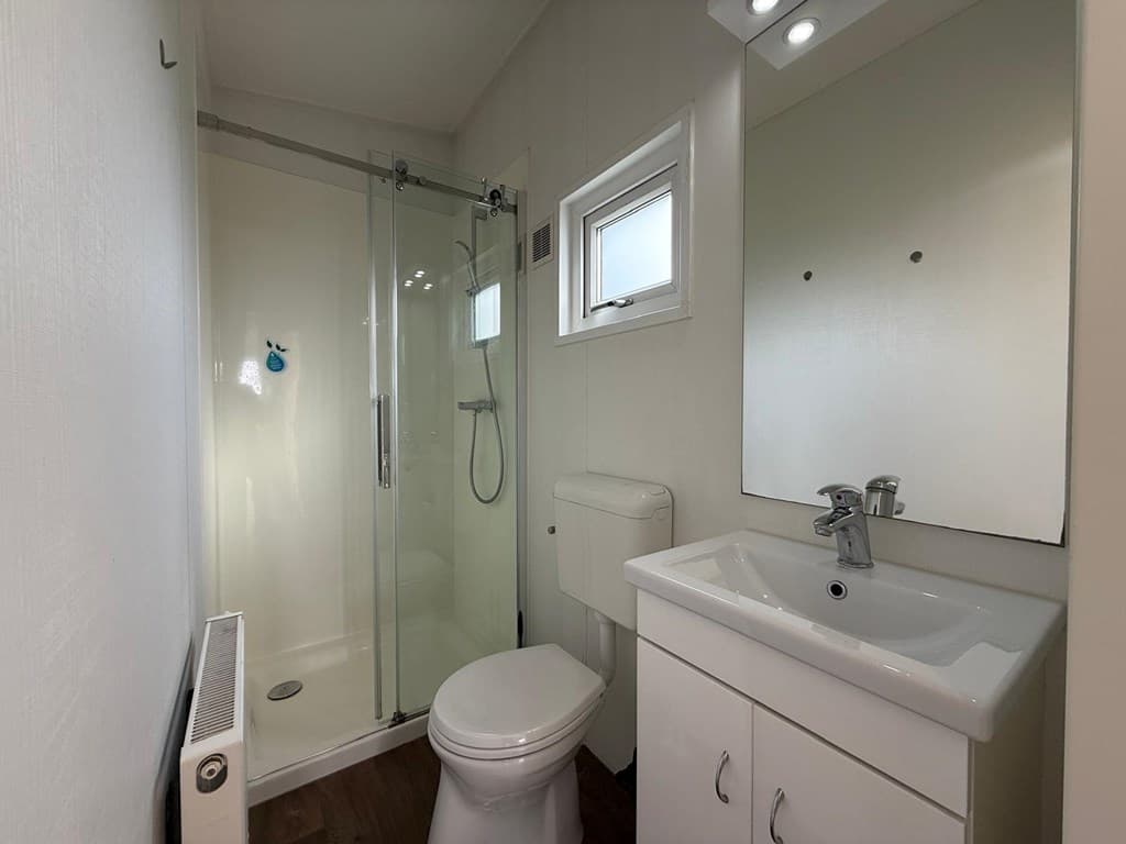 Moderne badkamer met douchecabine, wastafel en toilet, voorzien van een klein raam voor daglicht