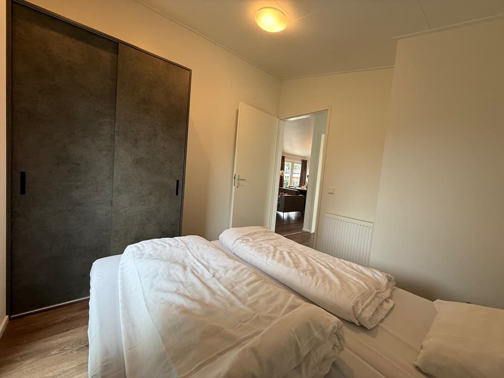 Slaapkamer met twee losse bedden, een kledingkast en toegang tot een andere ruimte.