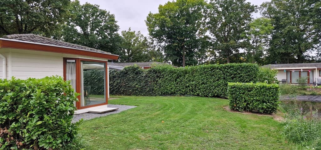 Vakantiehuis met grote tuin, omringd door hagen en bomen, nabij andere woningen in EuroParcs Limburg