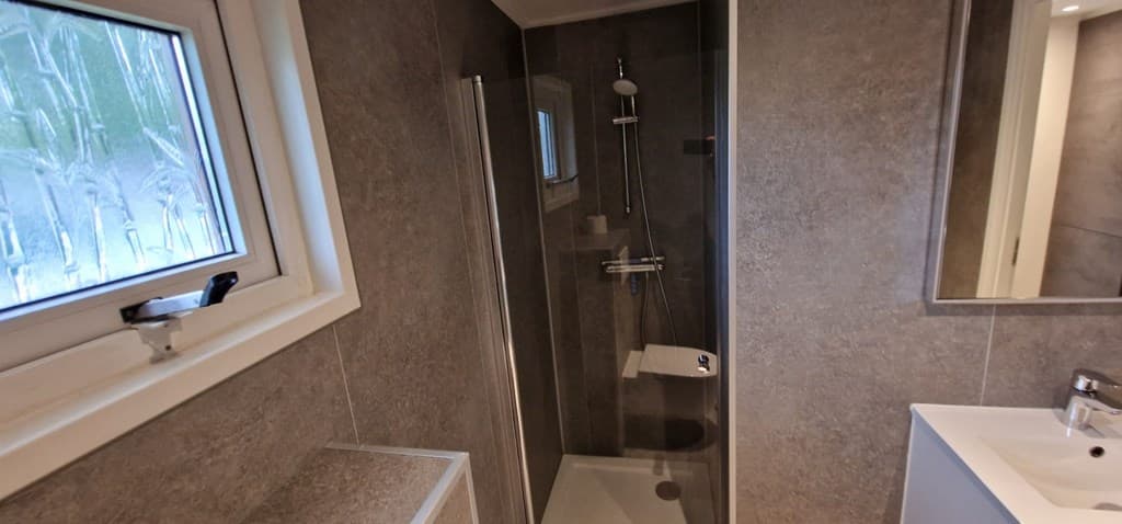 Moderne badkamer met inloopdouche, wastafel en raam voor natuurlijk licht.
