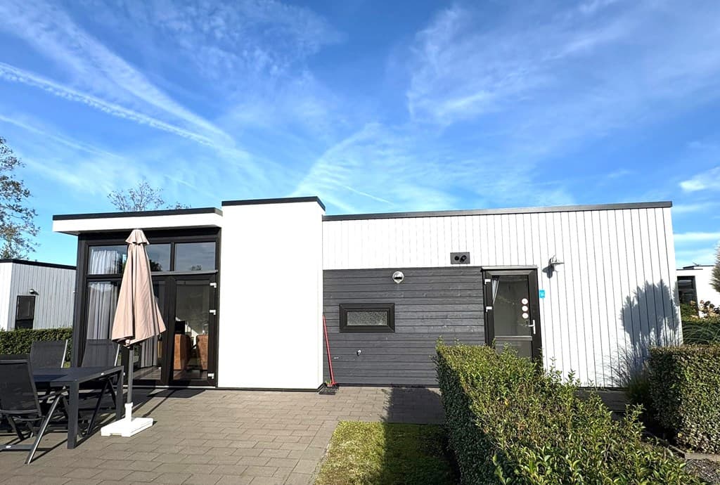 Moderne vakantiewoning met een terras, grijze gevelpanelen en een tuin met hagen aan EuroParcs Bad Hulckesteijn