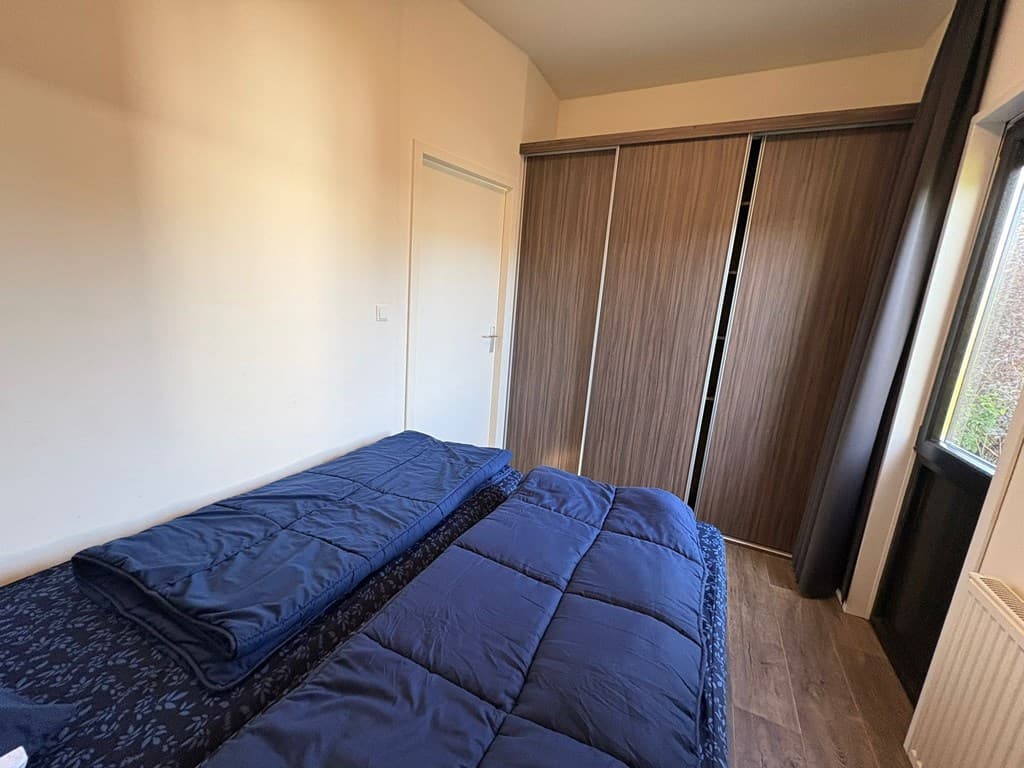 Slaapkamer met twee enkele bedden en een grote schuifkast tegen de muur