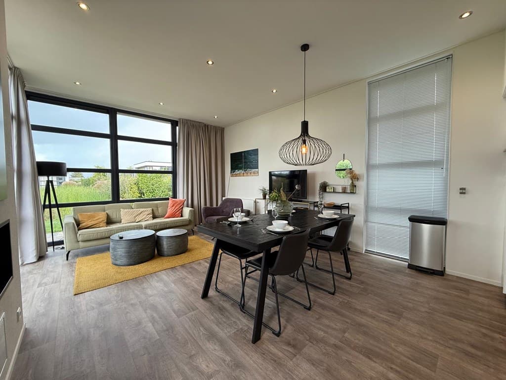 Modernewoonkamer met zithoek, eettafel en grote ramen voor veel lichtinval