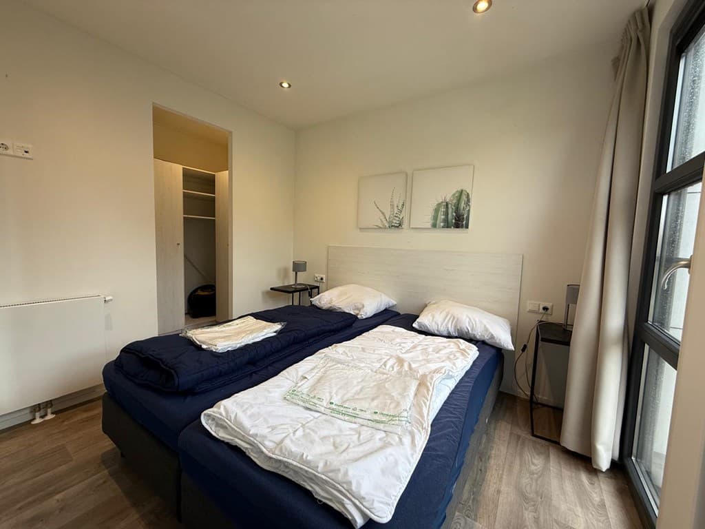 Slaapkamer met twee aparte bedden, kledingkast en ramen met uitzicht op buitenlucht.