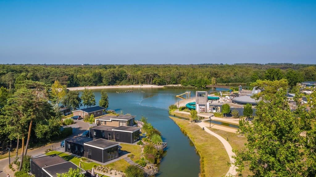 Luchtfoto van EuroParcs Zilverstrand met vakantiewoningen rond een meer en groene omgeving met speeltoestellen.