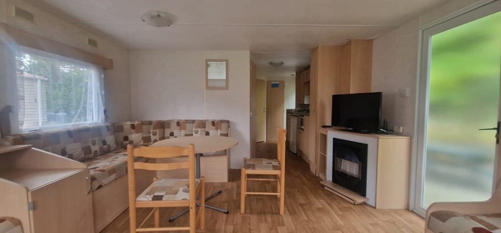 Woonkamer van een vakantiewoning met een zithoek, eettafel en toegang tot de keuken.