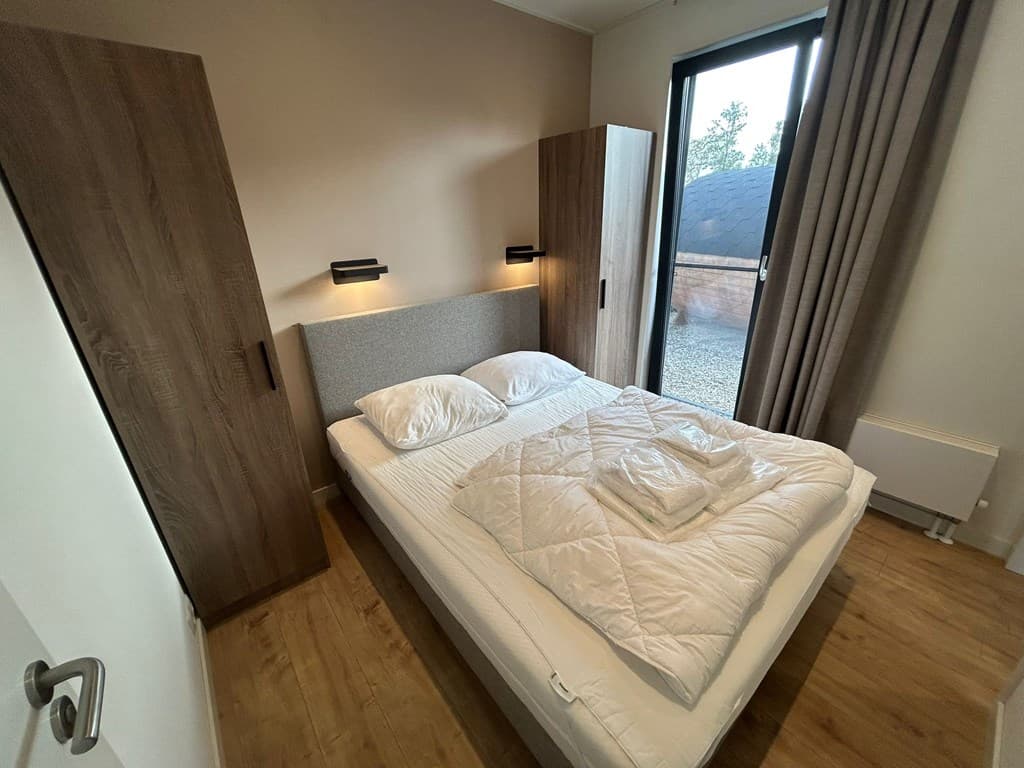 Slaapkamer met een tweepersoonsbed, twee kasten en een raam met uitzicht op de buitenomgeving