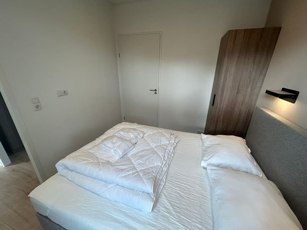 Slaapkamer met een tweepersoonsbed, kastenwand en een deur naar de gang.