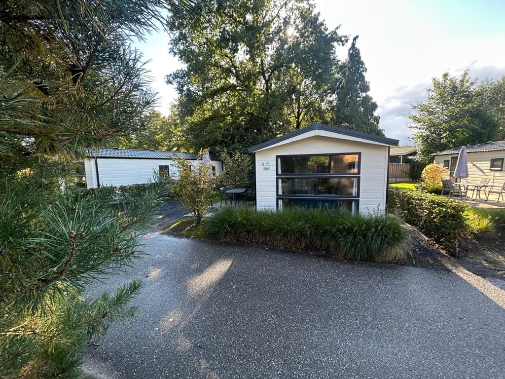 Witte vakantiewoning omringd door groen, met zichtbaar tuinmeubilair en een verhard pad in EuroParcs Zuiderzee