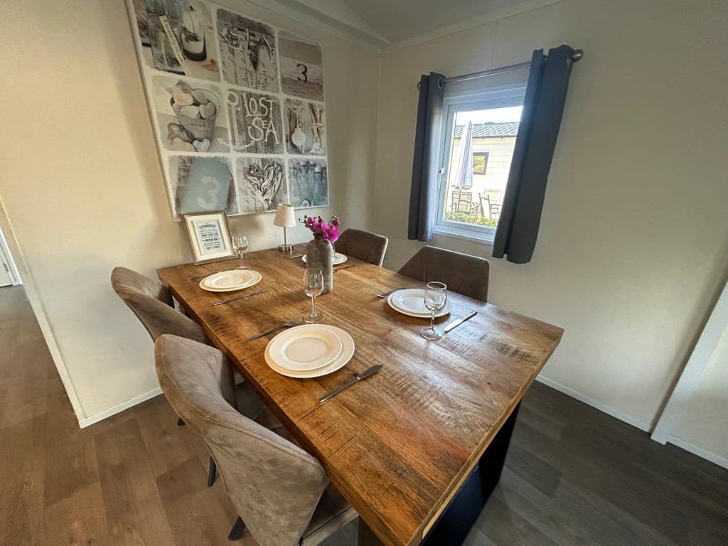 Eettafel met stoelen, vazen met bloemen op tafel, en een raam met uitzicht op een buitenruimte.
