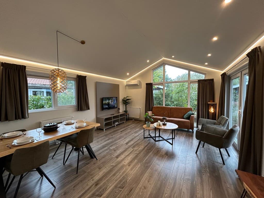 Moderne woonkamer met grote ramen, een zithoek, eettafel en rustige kleurenflora.