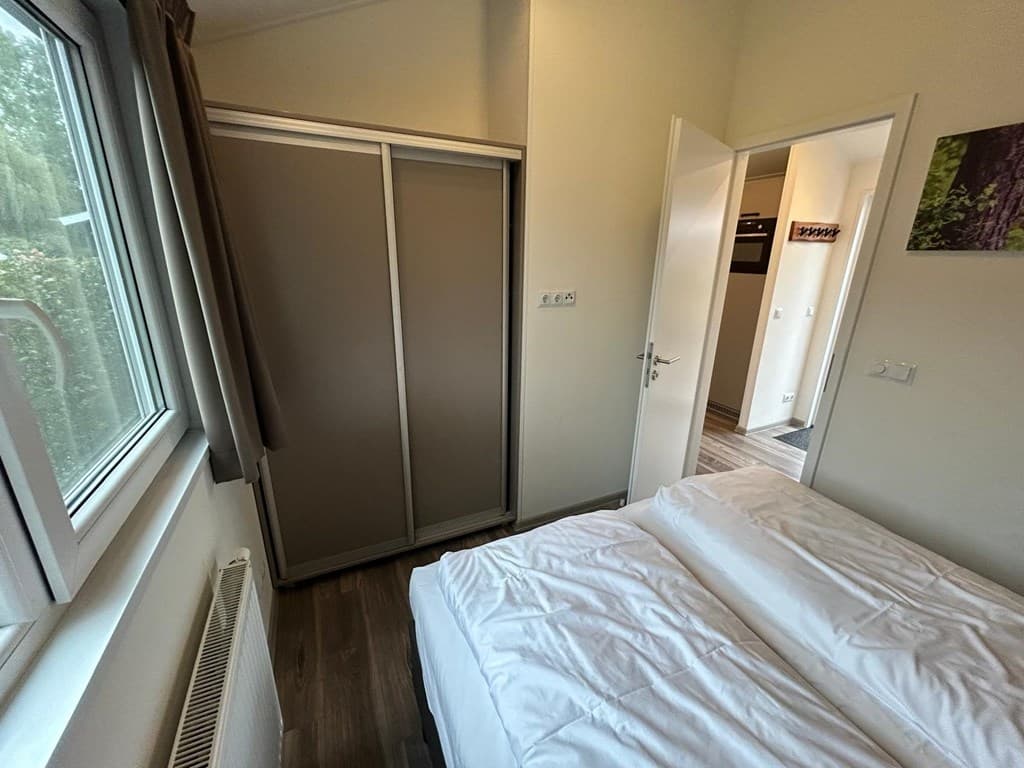 Slaapkamer met twee eenpersoonsbedden, kast en raam met uitzicht op buiten.