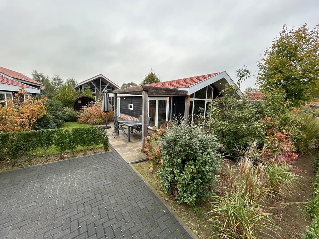 Gezellig huisje met tuin en terras, omringd door begroeiing en een stenen pad in een parkachtige omgeving