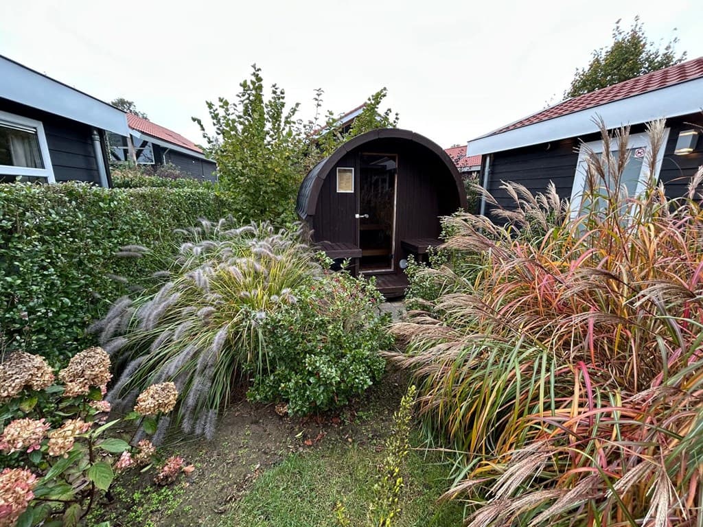 Buitenzicht van een sfeervol huisje omringd door groene begroeiing en kleurrijke planten in de tuin