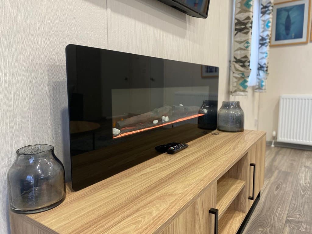 Moderne woonkamer met een strakke kast, een elektrische haard en decoratieve glazen vazen.