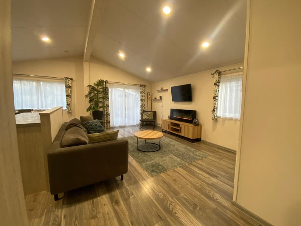 Gezellige woonkamer met een bank, salontafel, tv en slimme verlichting, met ramen die voor natuurlijk licht zorgen