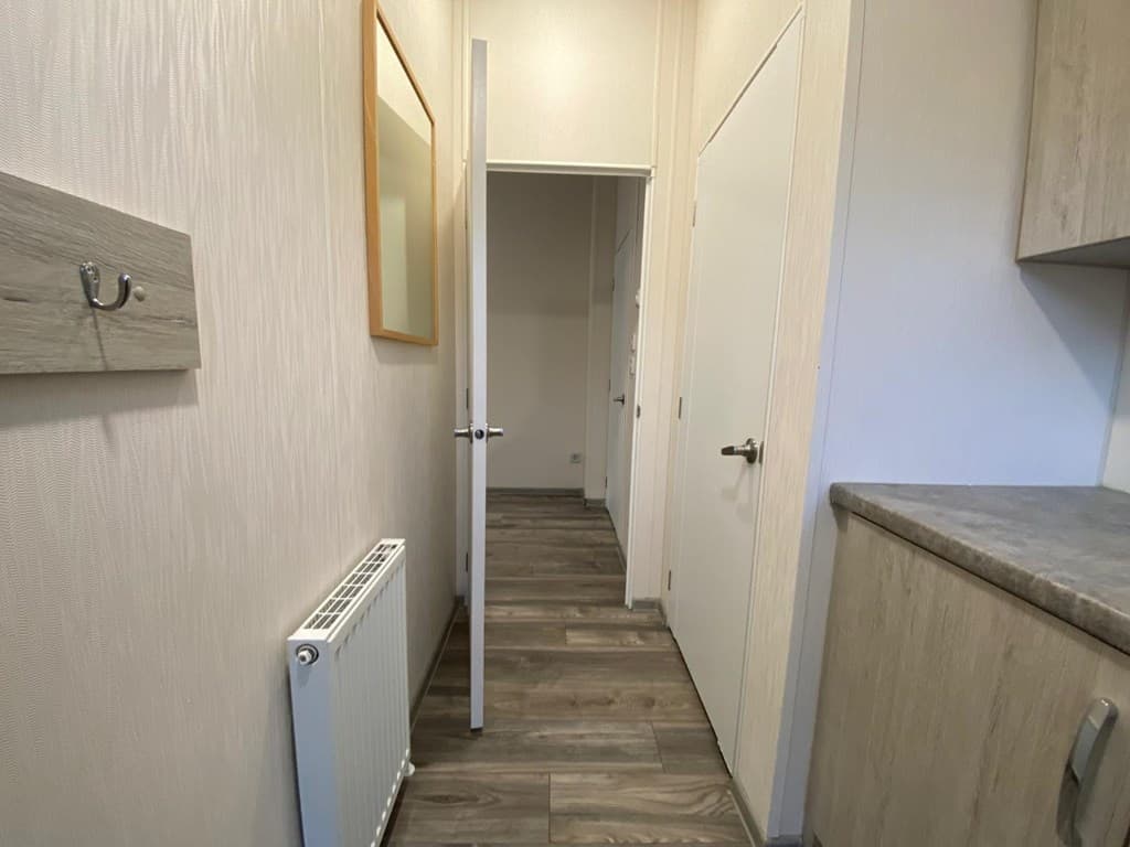 Inkomhal met een radiator, deuren naar andere ruimtes en een muur met een kapstok.