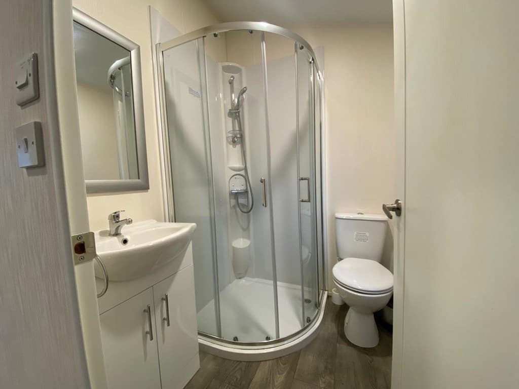Badkamer met wastafel, douchecabine en toilet in lichte kleuren en luchtige indeling.