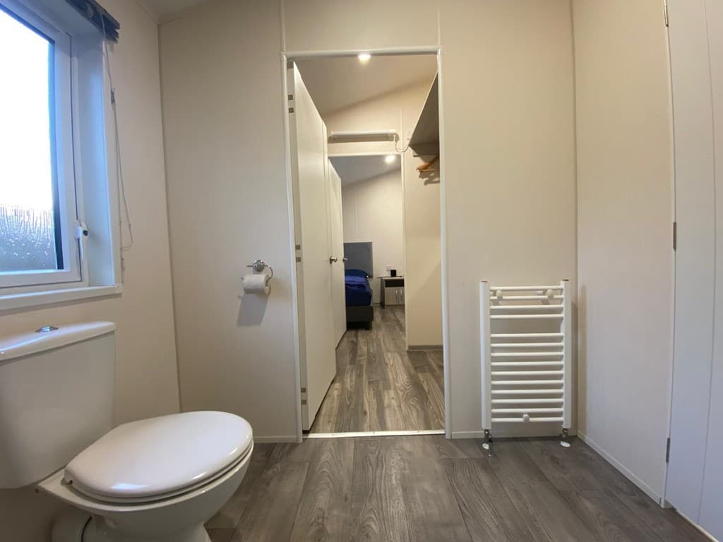 In een woning in EuroParcs Zuiderzee, met een toilet en een doorgang naar een slaapkamer met kledingrek.