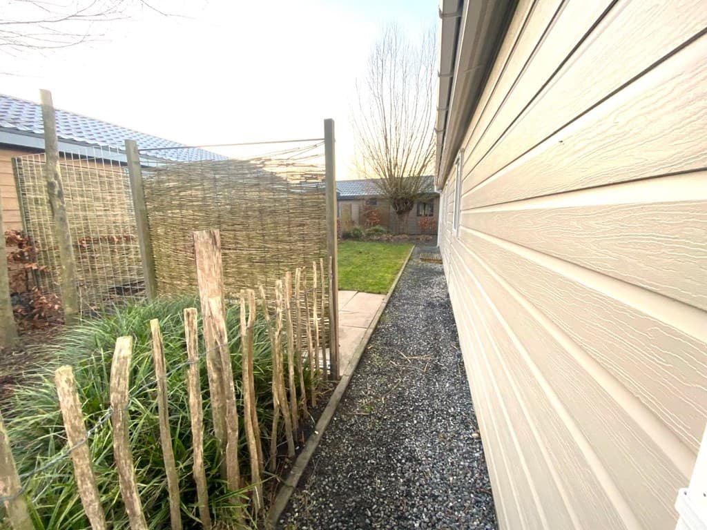 Smalle tuin met grindpad, schutting en gras, naast de gevel van de woning in EuroParcs Zuiderzee.