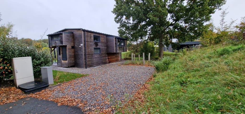 Houten vakantiehuis met een grindpad en een groen perceel, omringd door bomen en struiken in EuroParcs Zuiderzee