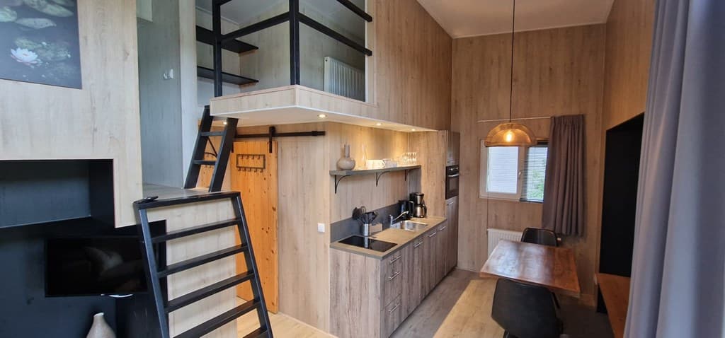 Interieur van een moderne woning met houten wanden, keuken, eetruimte en een vide met een trap.
