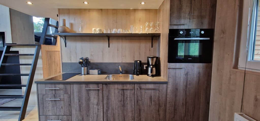 Moderne open keuken met houten kasten, spoelbak, kookplaat, oven en koffiezetapparaat, gelegen in een lichte ruimte