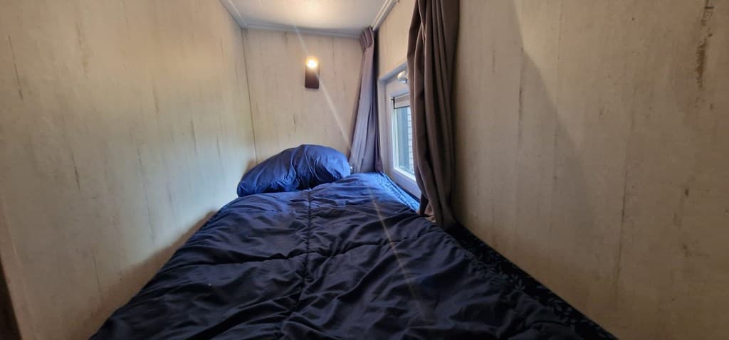 Slaapkamer met een eenpersoonsbed, lichte muren, een raam en verduisterende gordijnen.