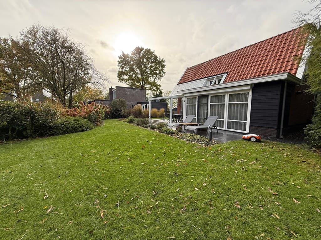 Woning met tuin en terras, omringd door groen, en een karakteristief rood pannendak.