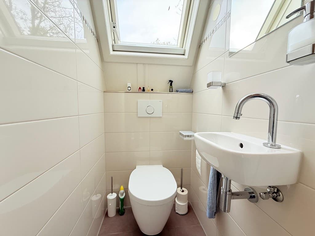 Modern toilet met wandcloset, fonteintje en grote ramen voor natuurlijke verlichting